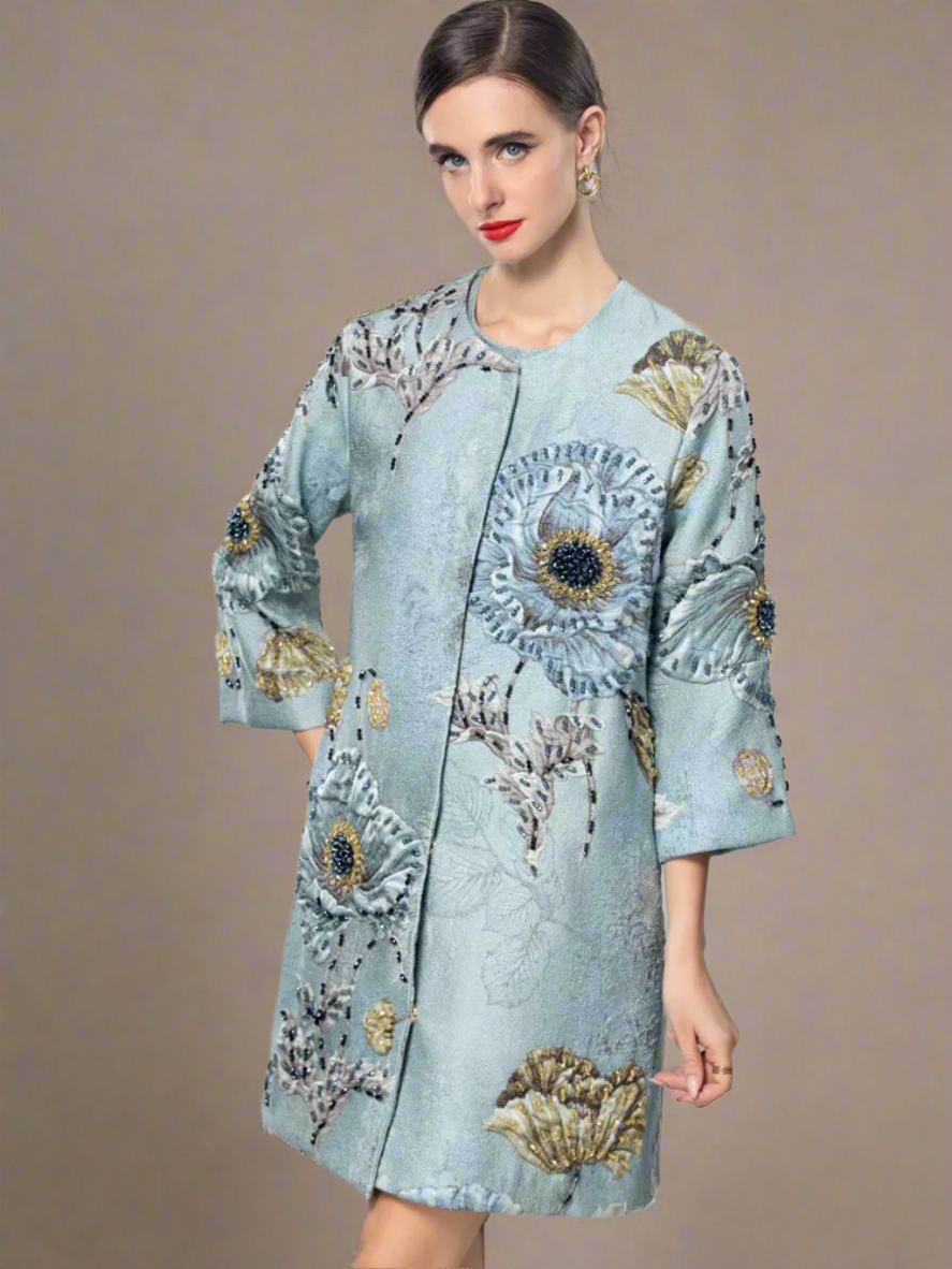Light blue embroidered coat with floral patterns on a gray background