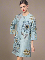 Light blue embroidered coat with floral patterns on a gray background